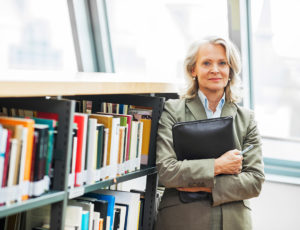 Mature woman standing next to the bookshelves