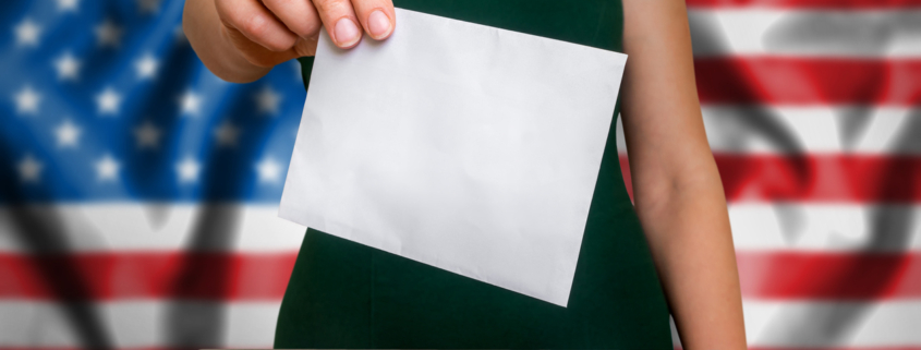 Election in United States of America - voting at the ballot box. The hand of woman putting her vote in the ballot box. Flag of USA on background.