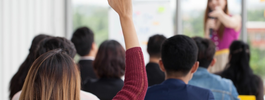 Woman raises hand during workplace training