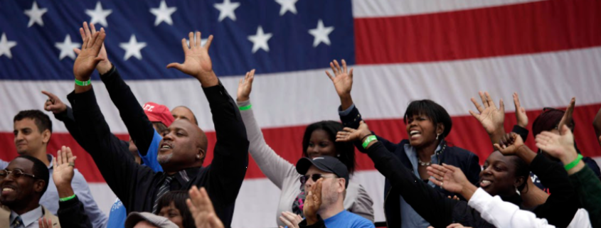 US flag behind a diverse group of campaign supporters