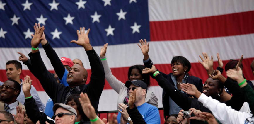 US flag behind a diverse group of campaign supporters