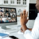 Working IDEAL blog about fair pay by geographic location | Image features a man working remotely at home on a video meeting with colleagues on the screen