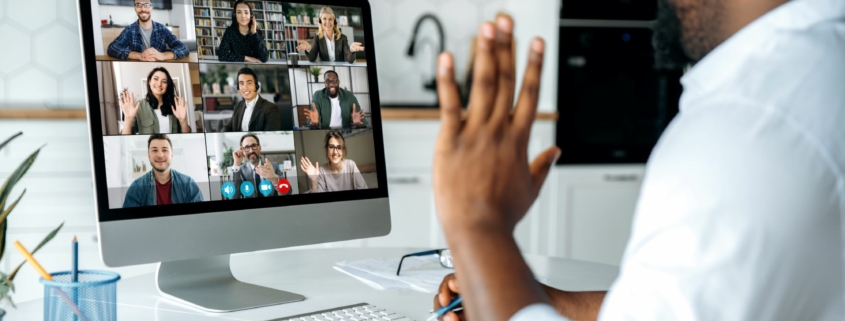 Working IDEAL blog about fair pay by geographic location | Image features a man working remotely at home on a video meeting with colleagues on the screen