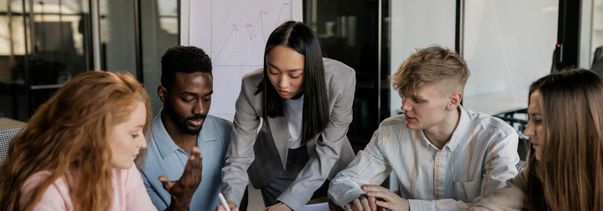 Working IDEAL blog - Equal Pay Day 2024 - employees collaborating around a table with paperwork