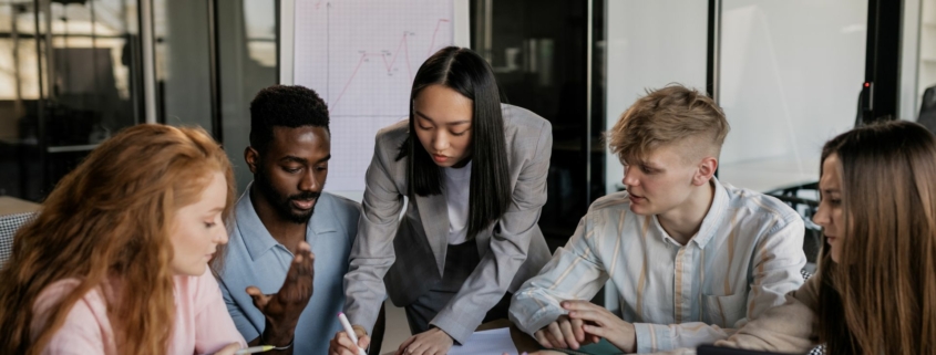 Working IDEAL blog - Equal Pay Day 2024 - employees collaborating around a table with paperwork