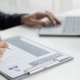 Working IDEAL blog about pay equity - image shows a person reviewing a resume with a laptop on the table